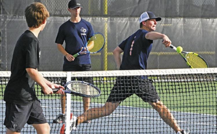 CALDWELL’S BRYCE BARR hits the ball while his doubles partner Blane Barr watches during their match against a Giddings duo. Tribune photo by Denise Squier