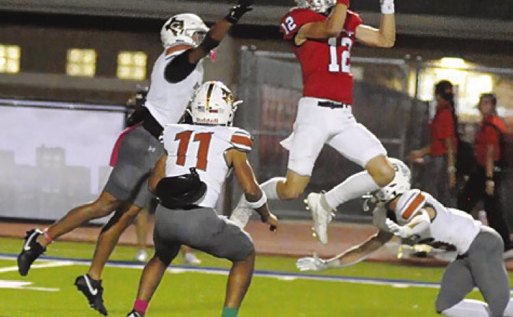 CALDWELL’S DYLAN CARTER, Zane Brown and Krush Strange defend as this Madisonville receiver makes a catch. Tribune photo by Denise Squier
