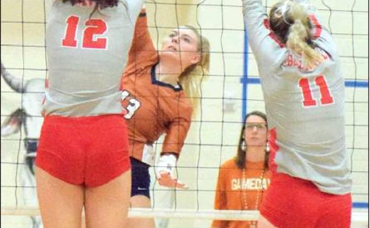 CALDWELL’S MARLEY MAURER hits the ball through the outstretched arms of Bellville’s Madison Morgan and Robbin Rice during Lady Hornets’ win over the Brahmanettes on Friday in Bellville.