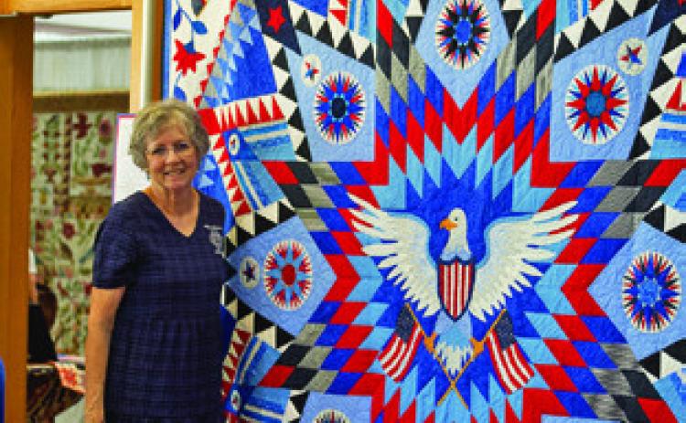 LOCAL QUILTER MARY WOLZ is pictured with her patriotic quilt at the Creative Memories Quilt Guild Quilt Show. Tribune photo by Sabine Lazo