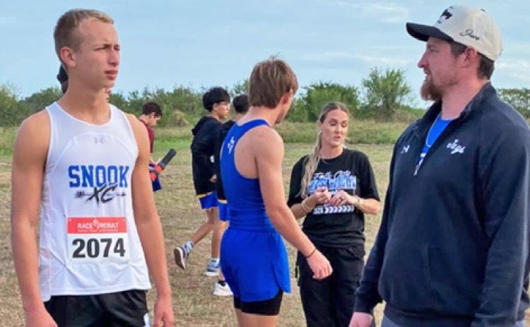 SNOOK’S BARRETT DUDENSING talks with his coach at Monday’s UIL Class 2A Regional Cross Country Championship in Corpus Christi. Dudensing placed fourth and qualified for the UIL State Meet.