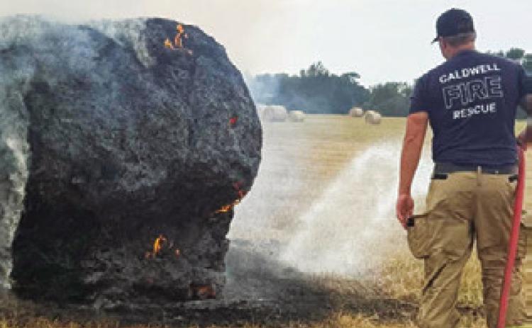 A CALDWELL FIREFIGHTER sprays water on this hay bale ignited on Thursday, Sept. 3, by a lightning strike on County Road 205. Only this bale was damaged out of a field of numerous bales at Andy Perry’s pasture, Caldwell Fire Chief Harry Bowers said.