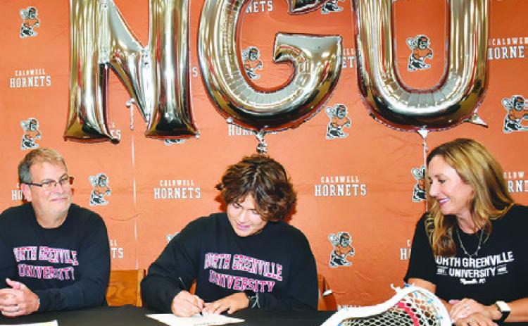 KIEFER ELLIS SIGNS his letter of intent with North Greenville University for a lacrosse scholarship. His joined by his parents David and Melanie Ellis. -- Tribune photo by Roy Sanders
