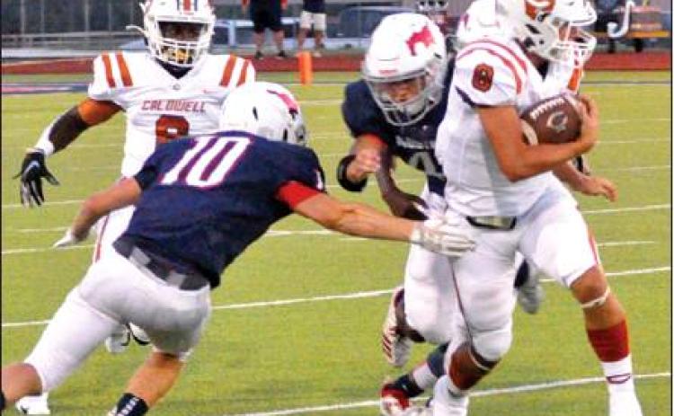 LOGAN KNESEK OF Caldwell carries the ball against Madisonville. Also pictured is Nicolas Johnson. Caldwell won 12-6 for its first win of the season. -- Tribune photo by Roy Sanders
