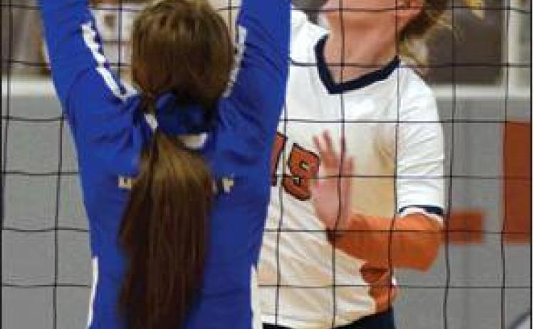 ELIZABETH SEE HITS the ball past a Rock-dale blocker Friday night at Hornet Gym. See had 11 kills for the Lady Hornets on Friday.