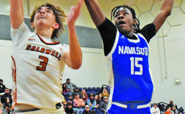 DYLAN CHAPMAN of Caldwell leaps high for this basket against Navasota. Tribune photo by Roy Sanders