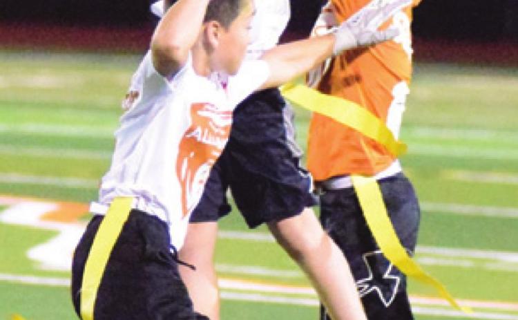 KRUSH STRANGE leaps to intercept the ball during the Alliance Youth Football League’s Division D3 Super Bowl last Thursday at Hornet Stadium. Also pictured are Caden Qualls, white jersey, and Hudson Novosad, orange jersey. -- Tribune photo by Denise Hornaday
