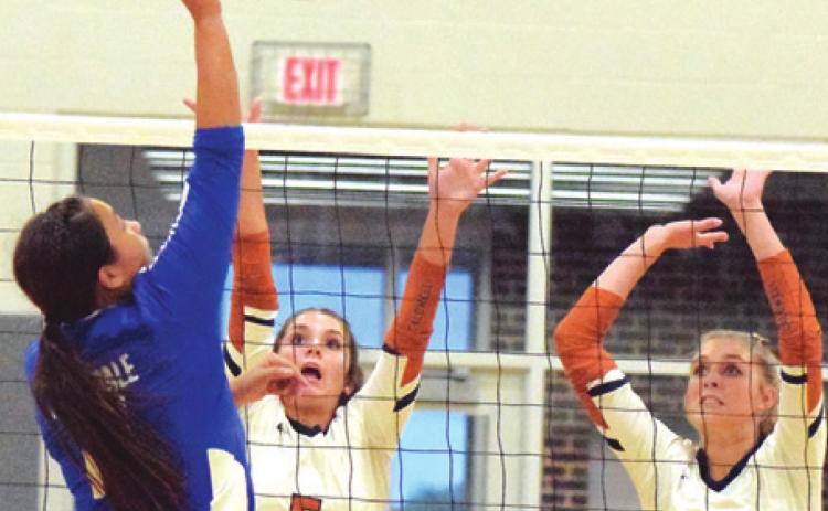 CALDWELL’S CAYLEE GARZA and Lexie Albright reach to try to block a hit from a Rockdale player last Tuesday during Caldwell’s win over the Lady Tigers. -- Tribune photo by Denise Squier