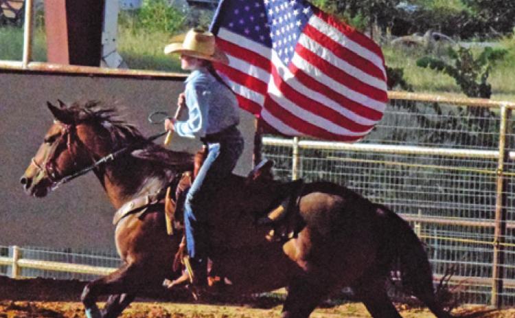 THE AMERICAN FLAG is carried around the arena to begin the annual Burleson County Youth Rodeo. --Tribune photo by Denise Hornaday