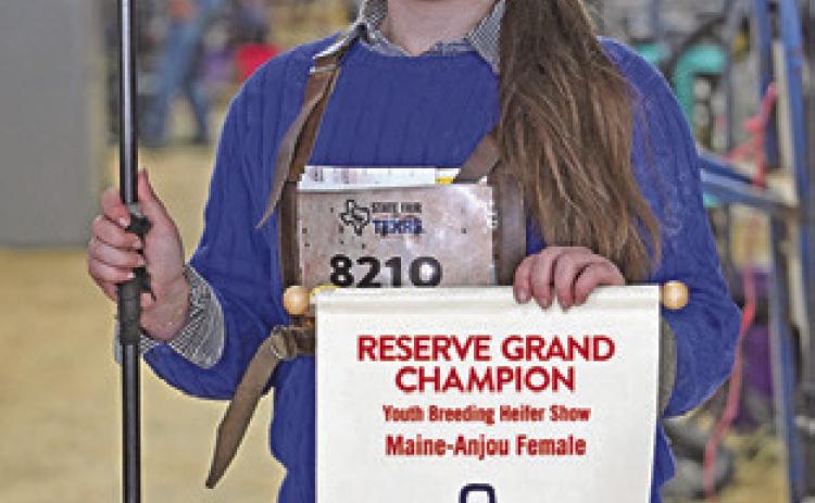 HADLEY HOWE poses with her Reserve Grand Champion banner for her Maine Anjou heifers at the 2026 State Fair of Texas. Photo courtesy of Burleson County 4-H