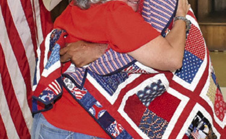 SHARON COLLEY hugs Robert Norris after he receives his Quilt of Valor at the VFW.