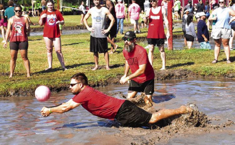 A MUD VOLLEYBALL player lunges for the ball right before he falls into a big mess.