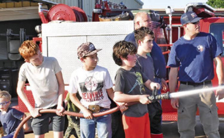 FUTURE FIREFIGHTERS SPRAY water under the supervision of Nathan Flippin and Jeff Baldwin on Saturday at the Deanville Volunteer Fire Department’s Community Night Out.