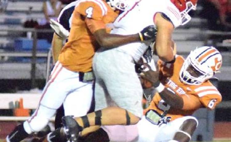 CALDWELL’S DONTAVIAN JOHNSON and Nicolas Johnson tackle the Columbus player after a big yardage gain for the Cardinals in the first half of Friday night’s game. -- Tribune photo by Denise Hornaday