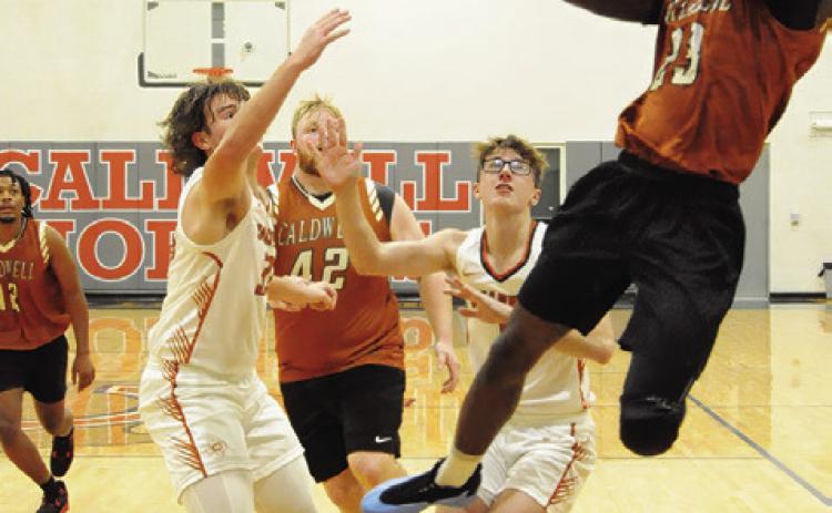SHAGARIUS HARRISON LEAPS high for this shot as varsity’s Koy Macik and Caden Zboril defend. Also pictured for the alumni are Deautre Burns and Chase Stewart. Tribune photo by Denise Squier
