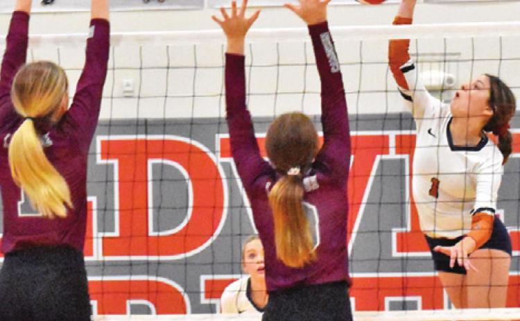 CALDWELL’S ASHLYN KELLUM hits the ball over two blockers last Friday during the Lady Hornets’ district loss to Cameron Yoe.